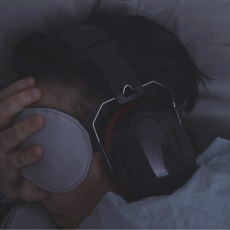 A person peacefully sleeping with headphones resting on their head, surrounded by a calm and serene environment.