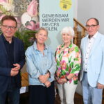 Vier ehemalige österreichische Minister stehen vor einem Transparent mit der Aufschrift „GEMEINSAM WERDEN WIR ME/CFS HEILEN“. Mit ihrem lächelnden Posieren im Ströck Feierabend in der Burggasse, machen sie darauf aufmerksam, wie ME/CFS in Österreich: Vier ehemalige Minister unterstützen die Petition zum PAIS-Aktionsplan.
